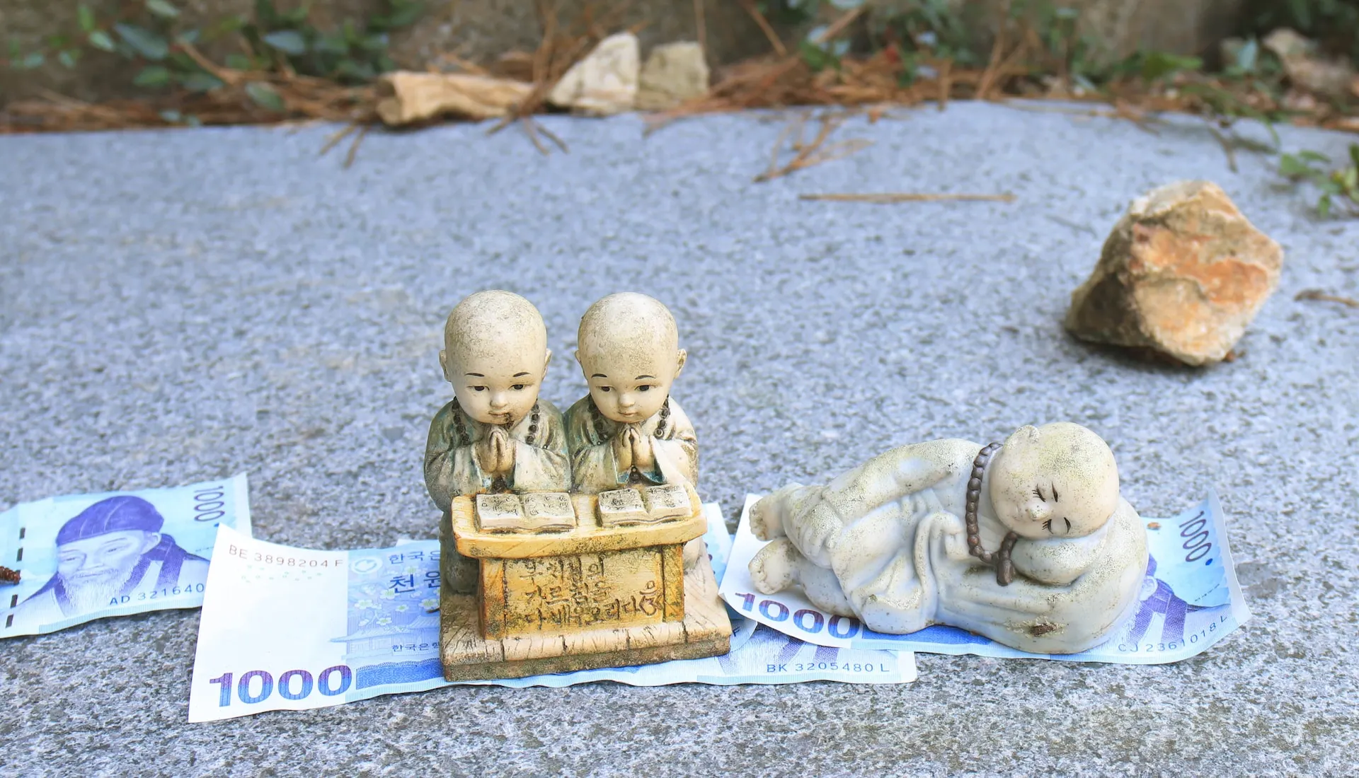 small korean statues used for prayer purposes sit on to of some money donated to the temple