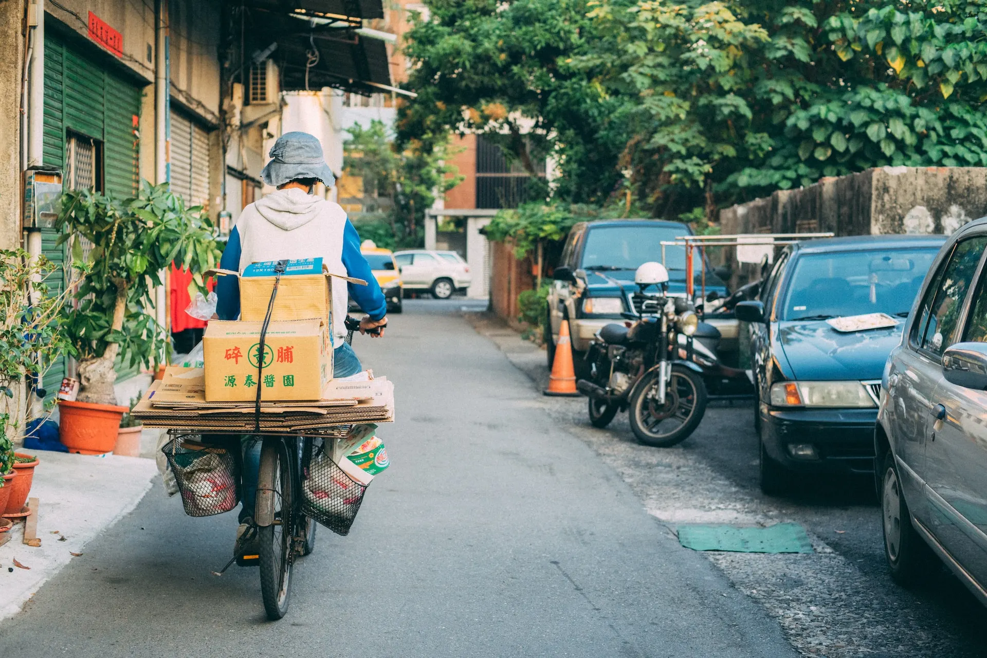 man riding a bicycle with cartons tied on the back